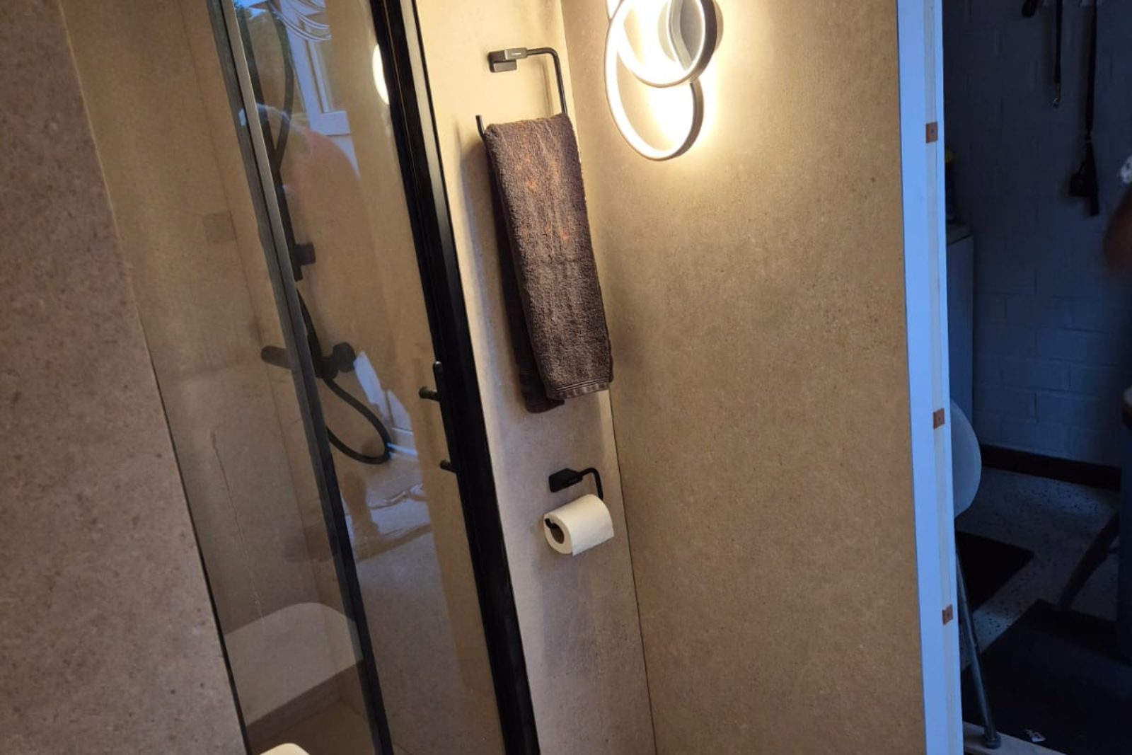 Afgewerkte doucheruimte met glazen wand en wandpanelen in steen-look, realisatie BB Schrijnwerken